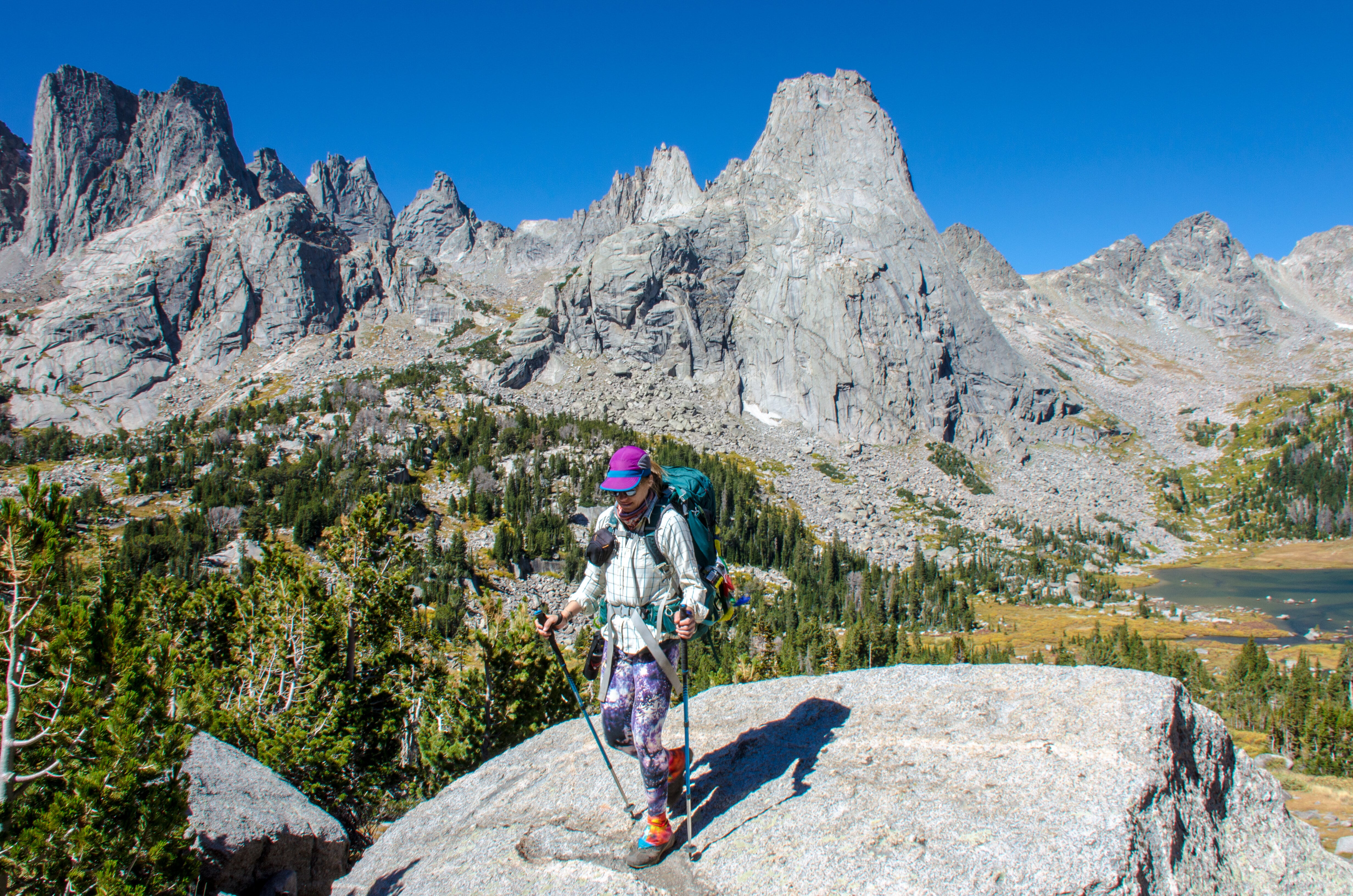 A person on a boulder hiking down a mountain.